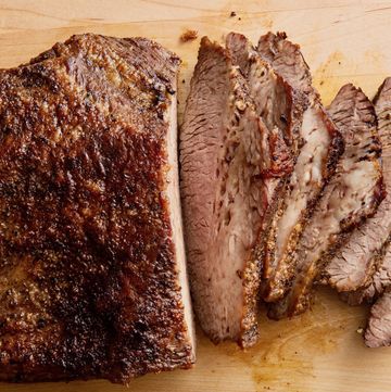 a well crusted, partially sliced beef brisket being sliced on a cutting board