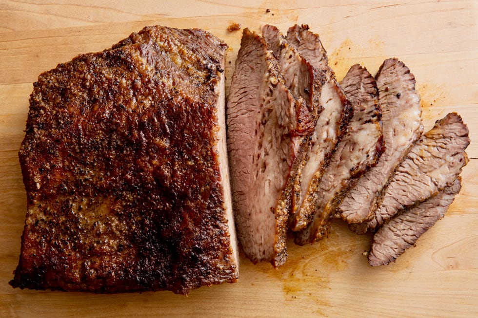 a well crusted, partially sliced beef brisket being sliced on a cutting board