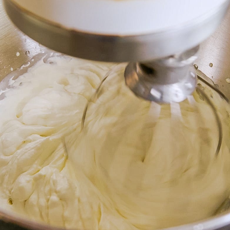 mixing fluffy whipped cream in a stainless steel bowl