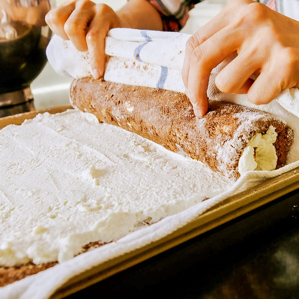 rolling a chocolate cake with cream filling using a towel