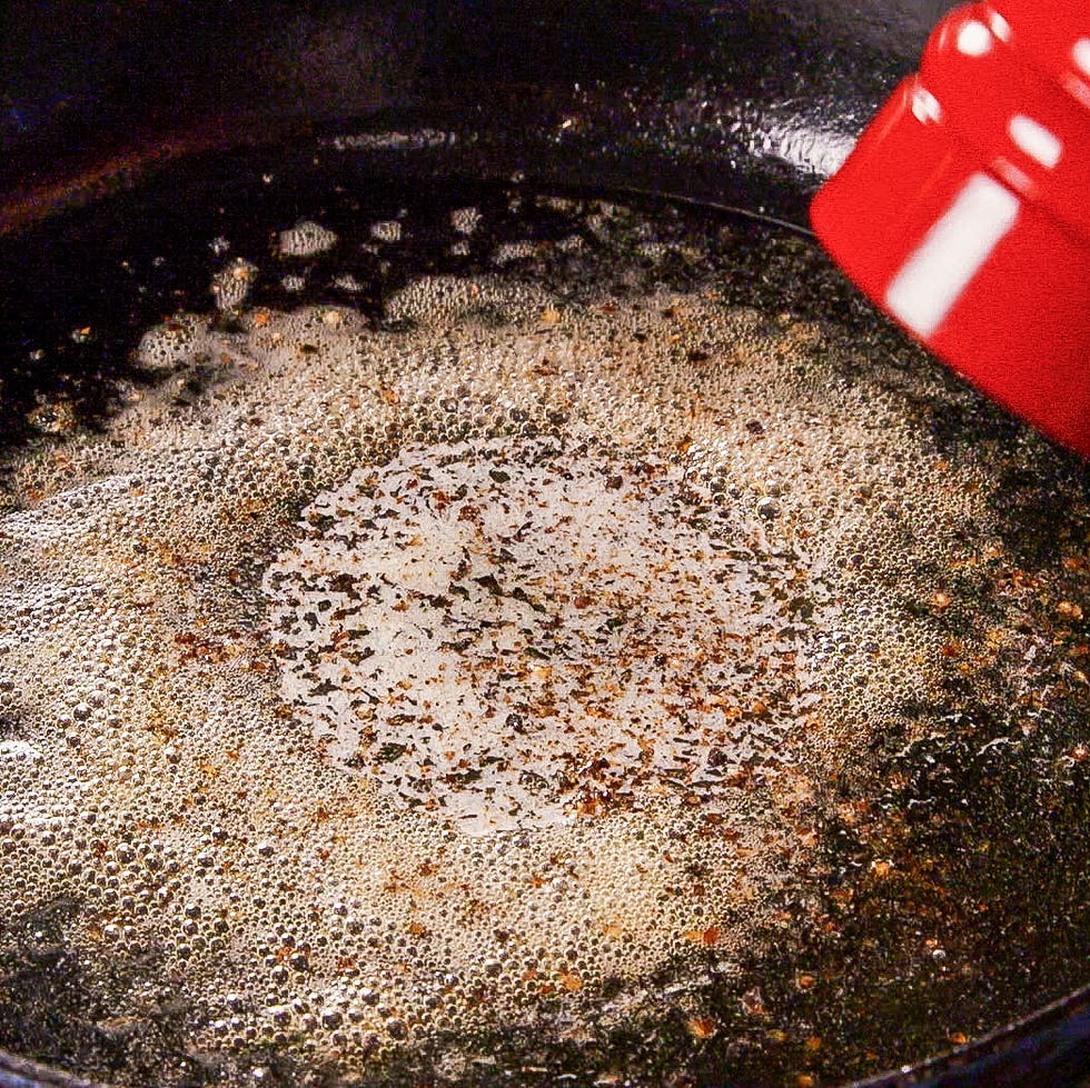 cooking oil with bubbles and seasonings in a skillet
