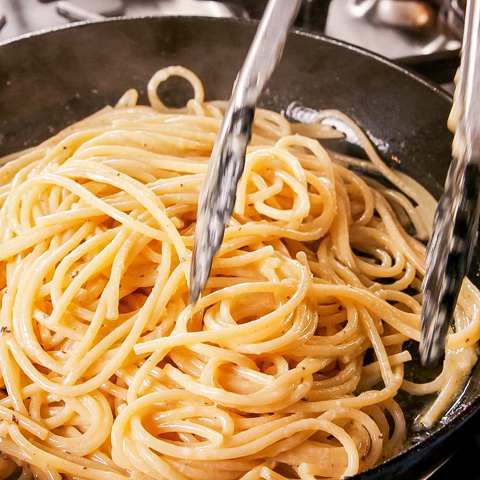 cacio e pepe being tossed in a skillet