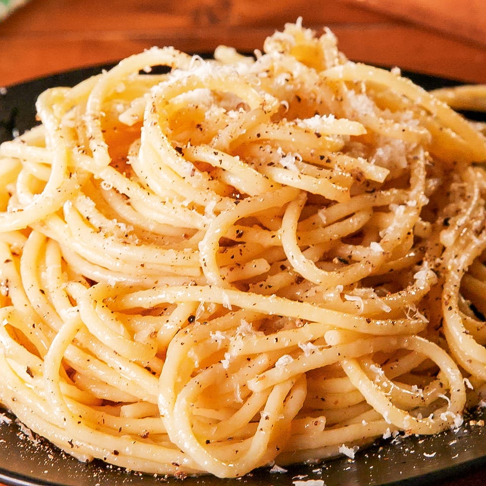 plate of spaghetti topped with cheese and pepper