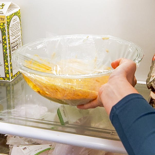 putting a bowl of spiced chicken in a fridge