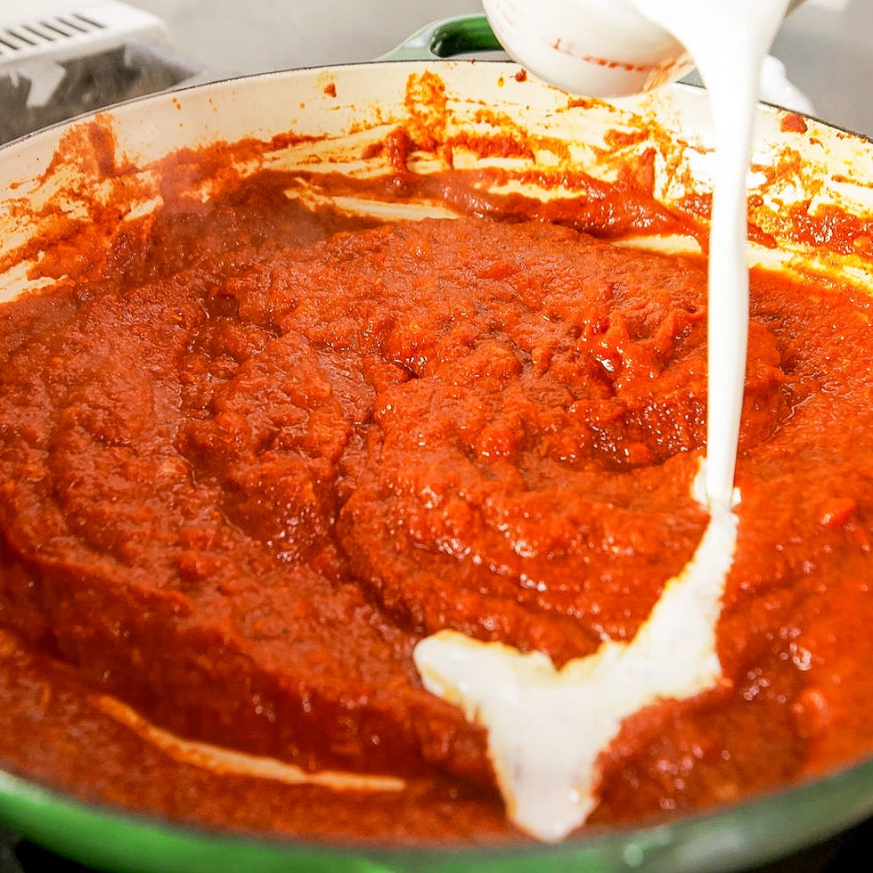 sauce mixing in a green cooking pot with cream being added