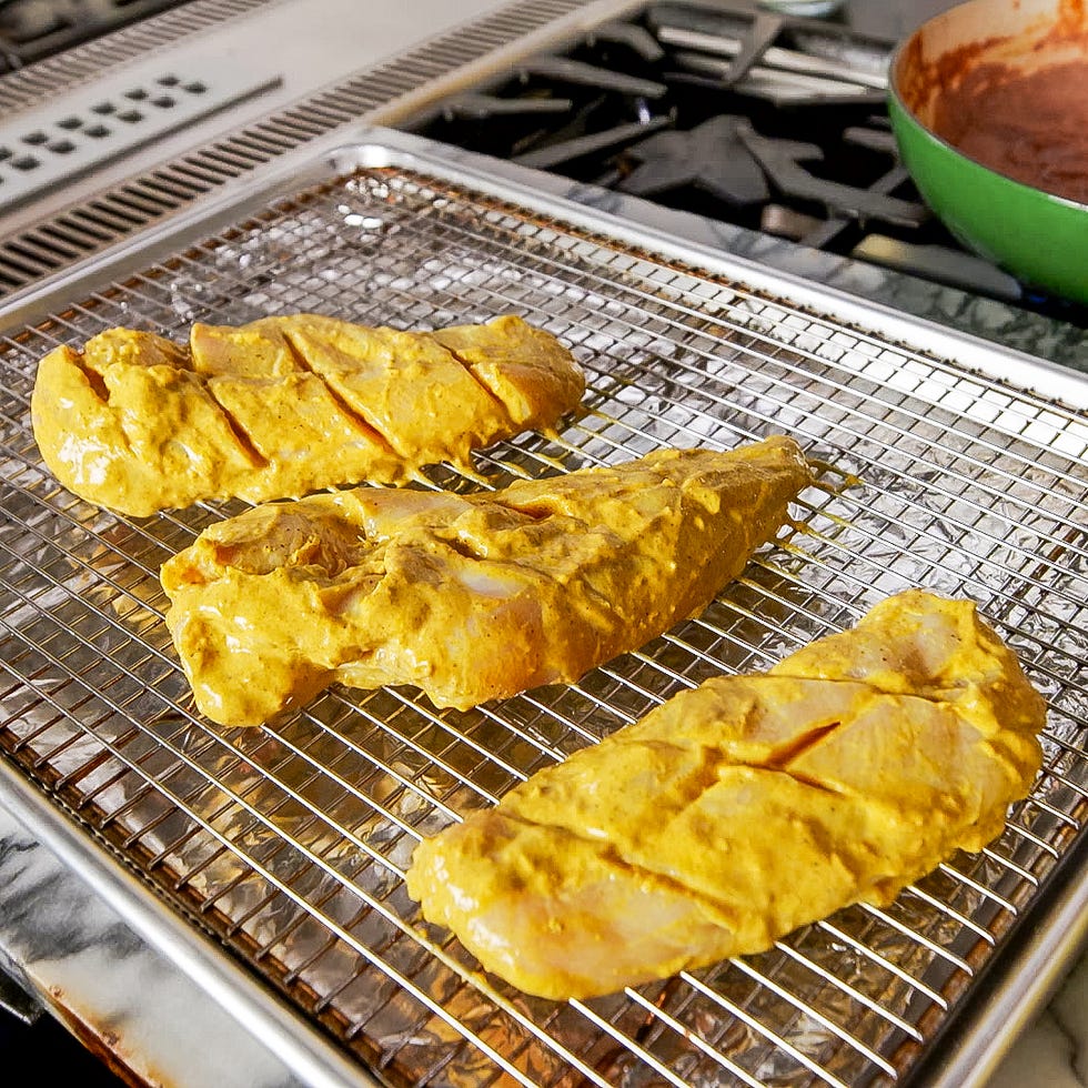 marinated chicken fillets on a wire rack in a kitchen setting