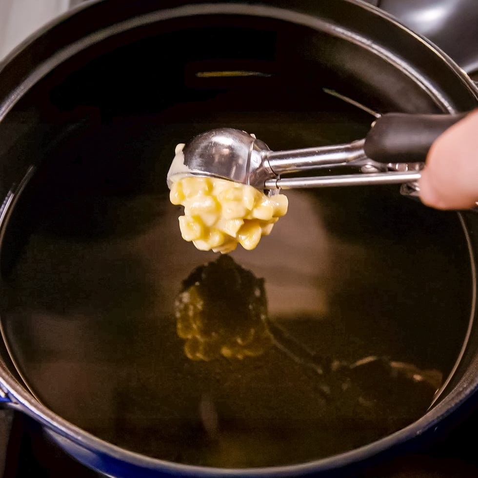 scoop of corn dough above bubbling oil in a pan