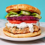 salmon burger topped with tomatoes, red onion, cucumber, and a yogurty sauce on toasted pita