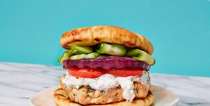 salmon burger topped with tomatoes, red onion, cucumber, and a yogurty sauce on toasted pita