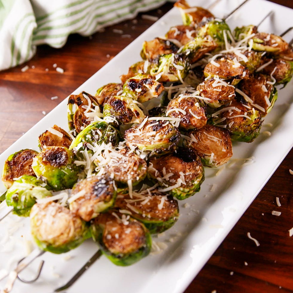 grilled brussels sprouts skewers topped with grated cheese on a serving platter