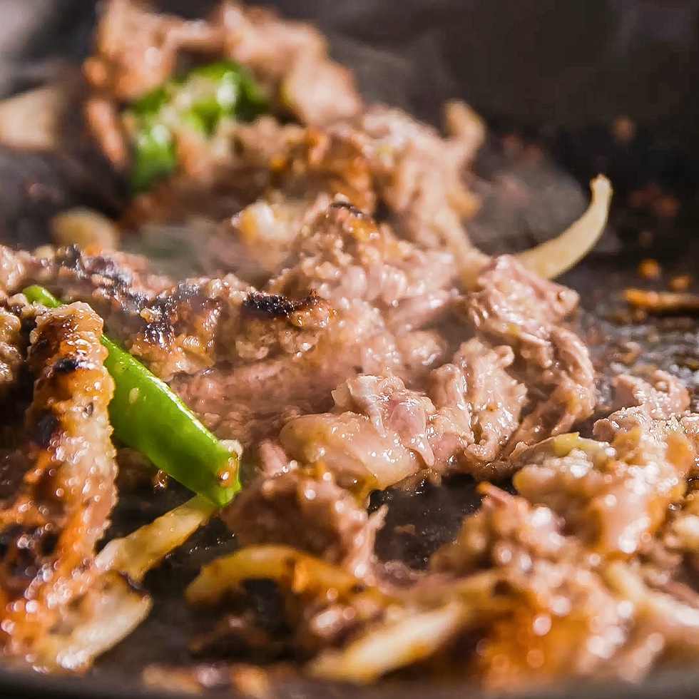 sizzling beef strips in a skillet with vegetables
