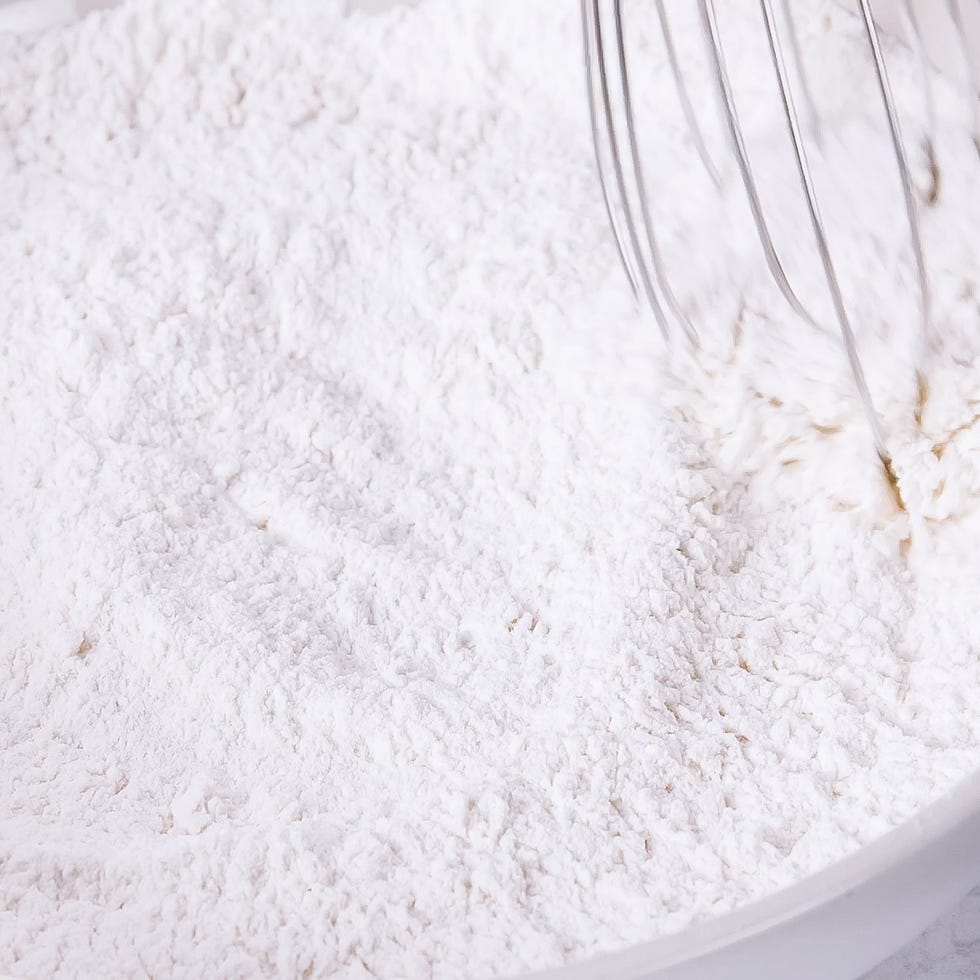 whisk stirring a bowl of white flour