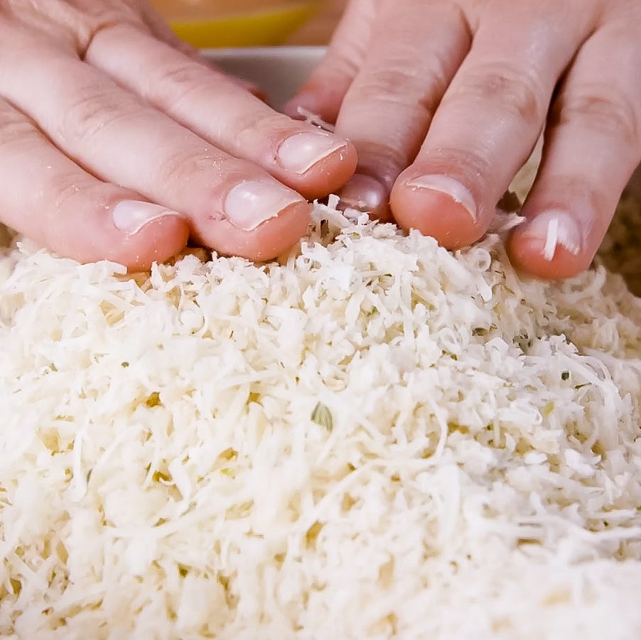 hands pressing down on a mound of shredded ingredients