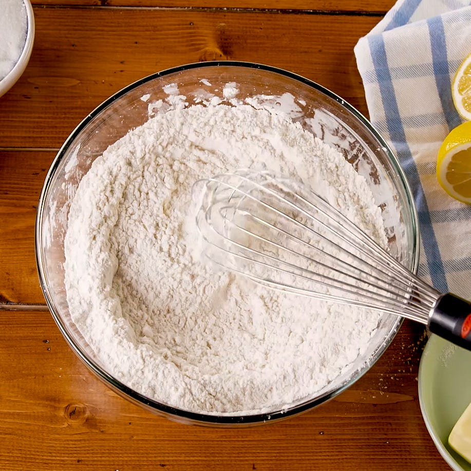 bowl of flour with a whisk on a wooden surface
