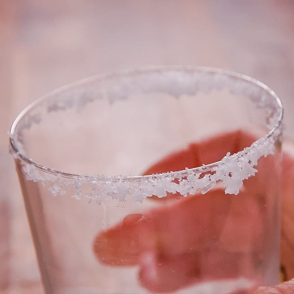 a glass with a salted rim being held by a hand