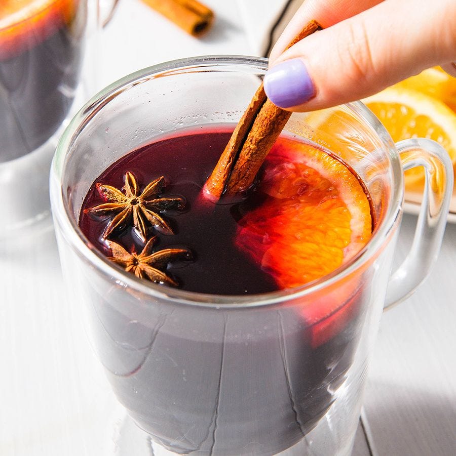 a person stirring mulled wine in a glass mug