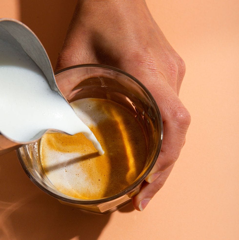 a hand holding a glass of liquid