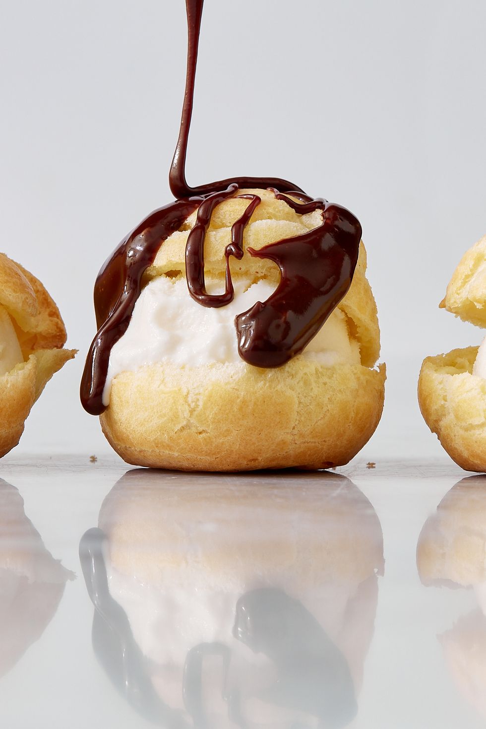 profiteroles drizzled with chocolate and filled with vanilla ice cream