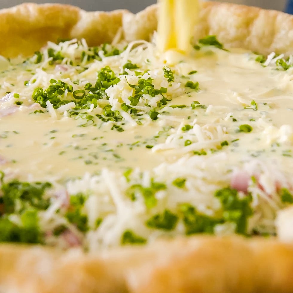 filling a pie crust with a mixture of cheese herbs and liquid ingredients