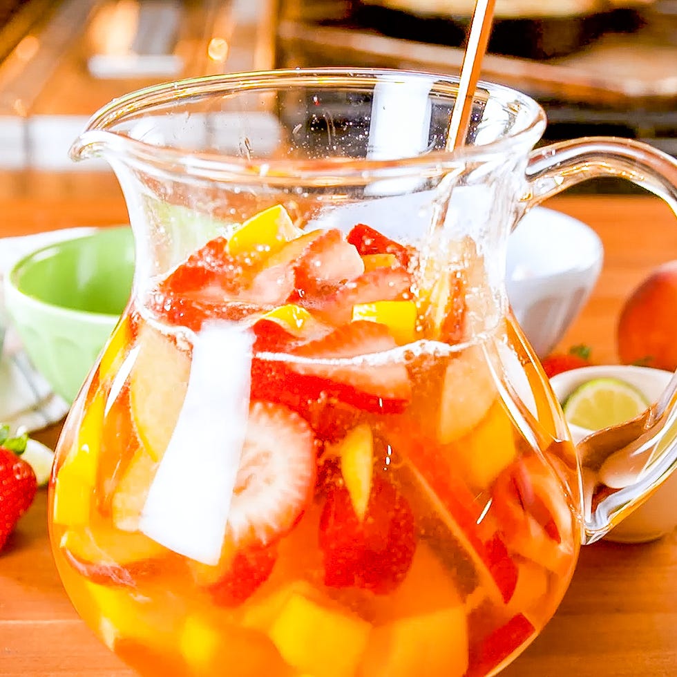 fruitfilled beverage in a pitcher with additional fruits in the background