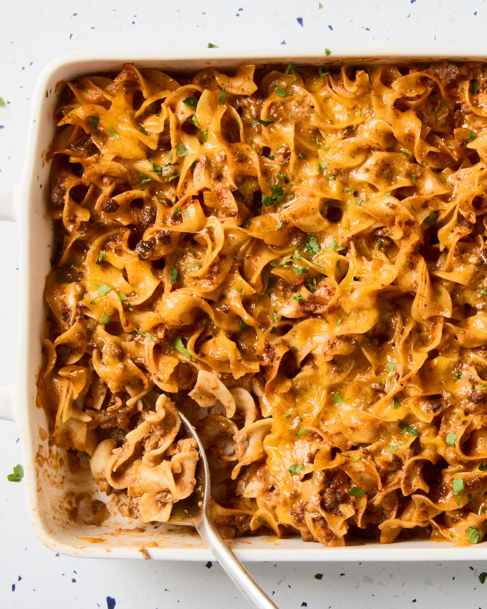 beef noodle casserole topped with melted cheddar and parsley in a casserole dish