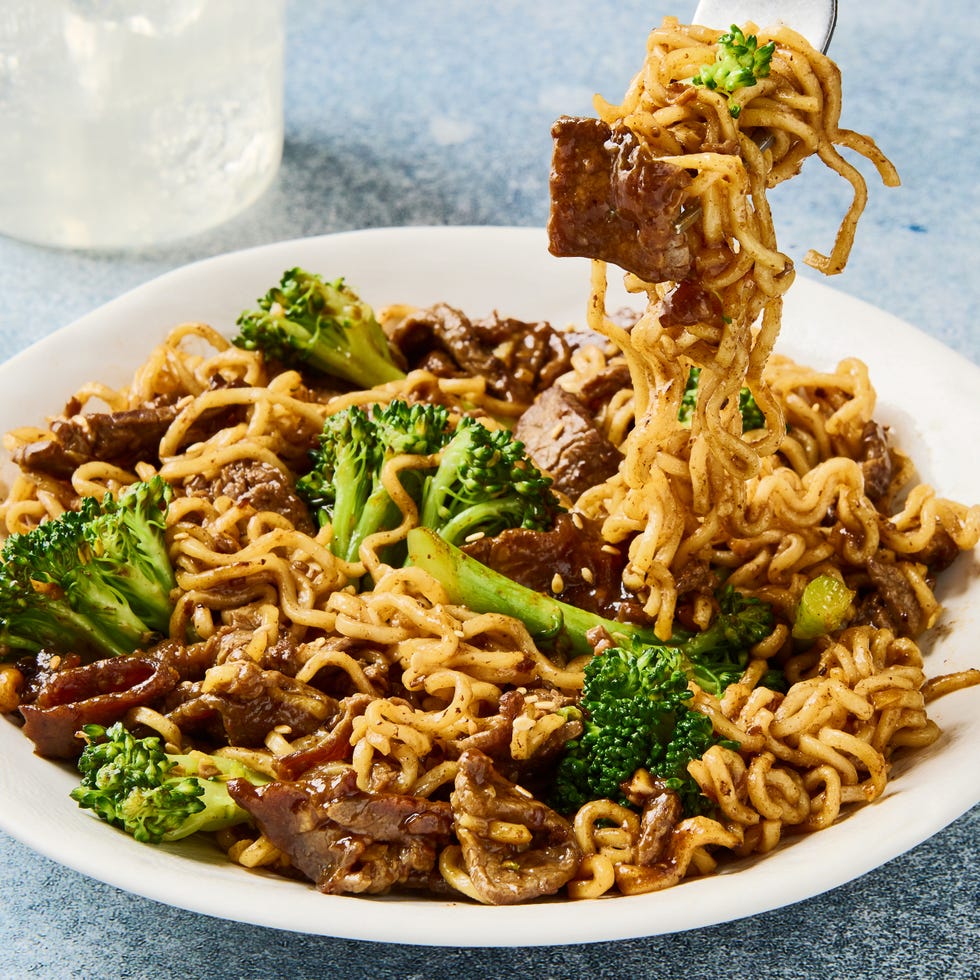 beef and broccoli ramen on a fork above a plate