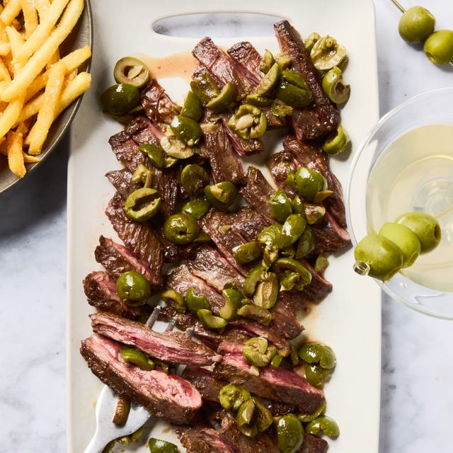 Dirty Martini Steak Frites seared skirt steak topped with buttery green olive, gin, and vermouth sauce and served with crispy golden french fries
