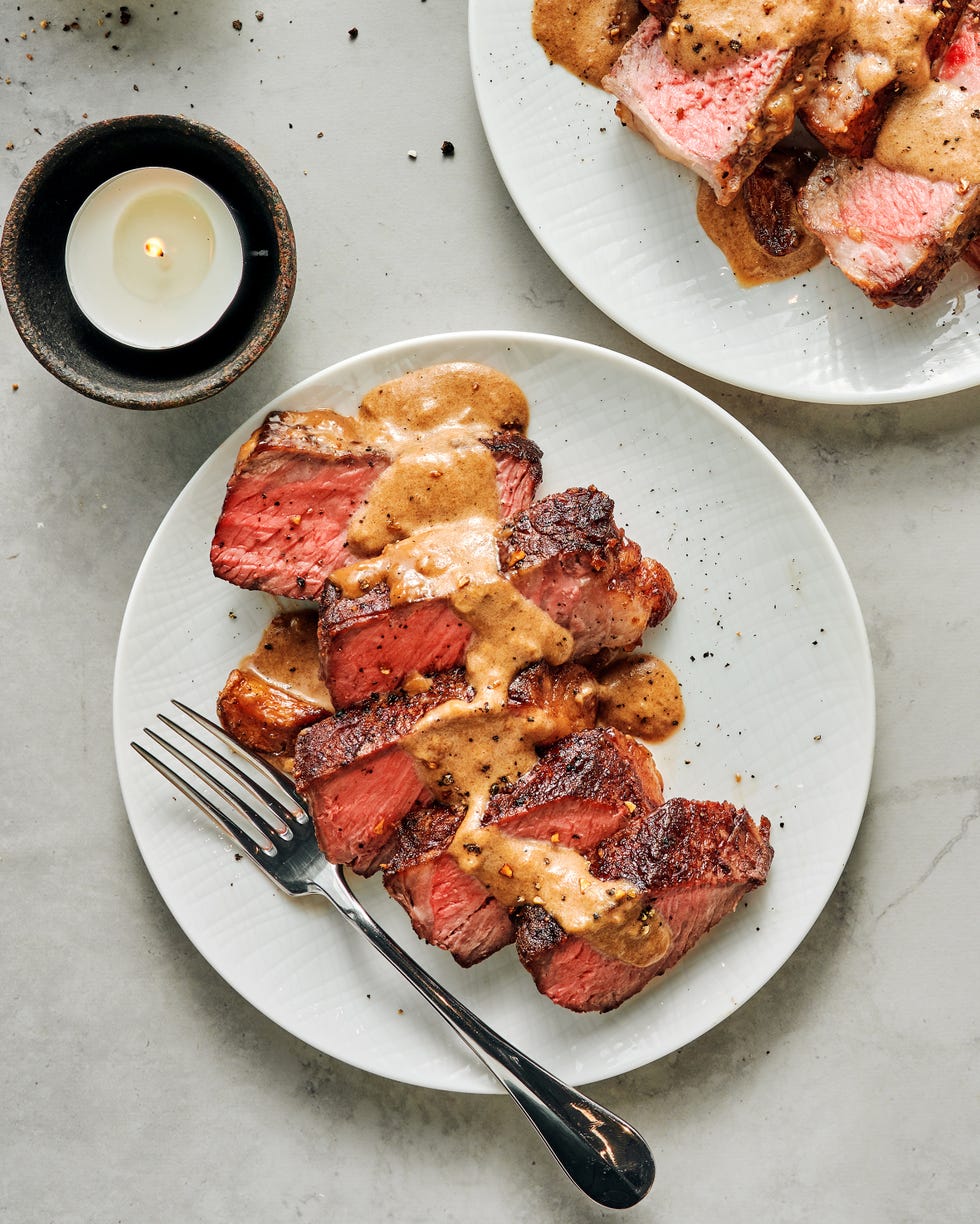 sliced steak with bourbon garlic cream sauce on a white plate