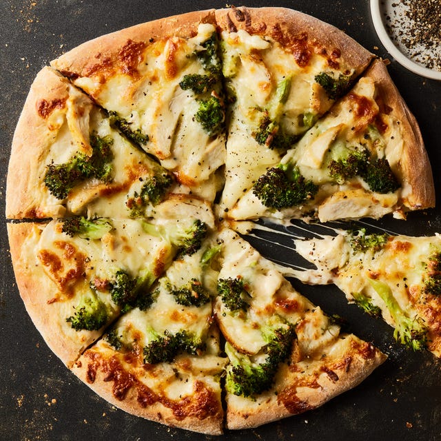 chicken broccoli alfredo pizza cut into slices on a black sheet pan