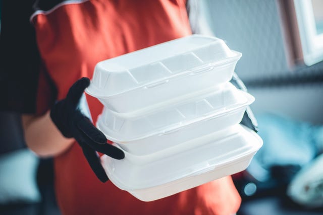 delivery woman with protective medical mask and gloves holding food box