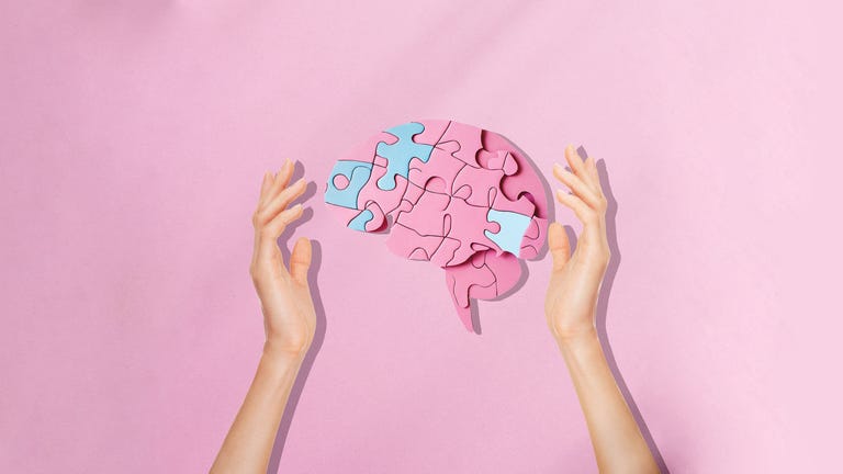 hand protecting a jigsaw puzzle brain, dementia mental health concept