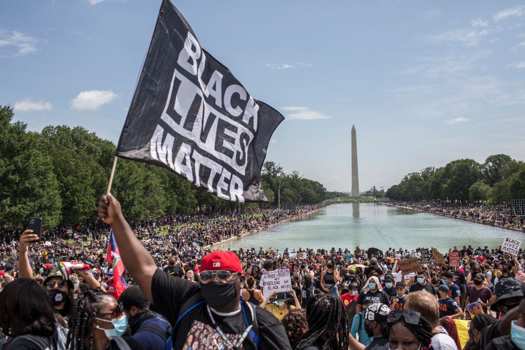 a demonstrator holding a flag with black lives matter