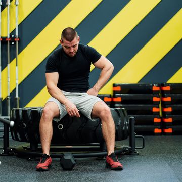 demotivated strong sporty man resting on gym bench