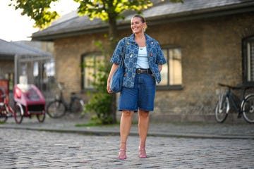 copenhagen, denmark august 10 janka polliani wears crystals pendant earrings, a blue and ripped gg monogram print pattern short sleeves denim shirt from gucci, a pale blue tank top from prada, a blue faded denim shoulder bag from chanel, a black shiny leather belt, navy blue denim knees shorts, pink shiny leather strappy heels mules with embroidered rhinestones heart details , outside ganni, during the copenhagen fashion week springsummer 2024 on august 10, 2023 in copenhagen, denmark photo by edward berthelotgetty images