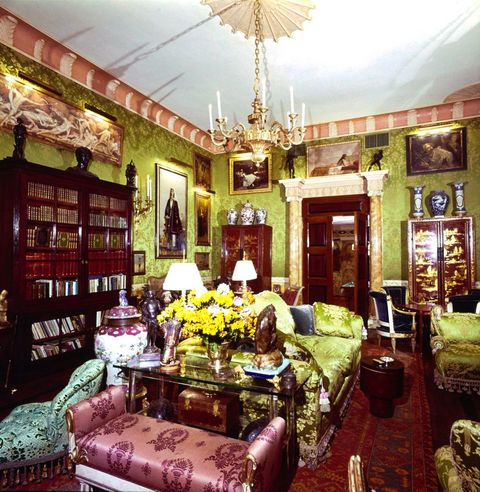 vogue, february 01, 1977   a reverse view of the living room of the upper east side, new york, new york, apartment of robert denning and vincent fourcade, owners of the interior designer firm denning  fourcade, inc the style of the 40 long x 25 wide x 15 tall ornate room is described as a louis seize european palais it includes green silk damask walls, a brass chandelier, green and white brocade satin upholstered furniture, a large wooden bookcase with glass paned doors, multiple paintings hung all over the walls, marble columns framing the doorway, and a large red oriental rug horst p horstconde nast via getty images