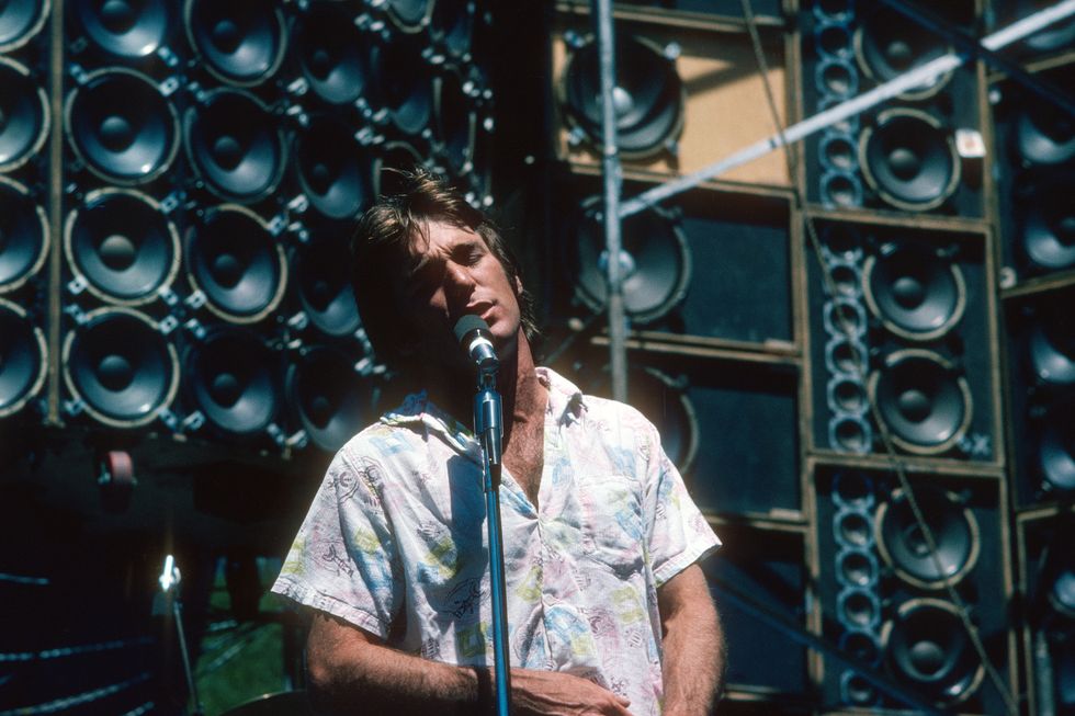 a man stands on a stage and sings into a microphone on a stand