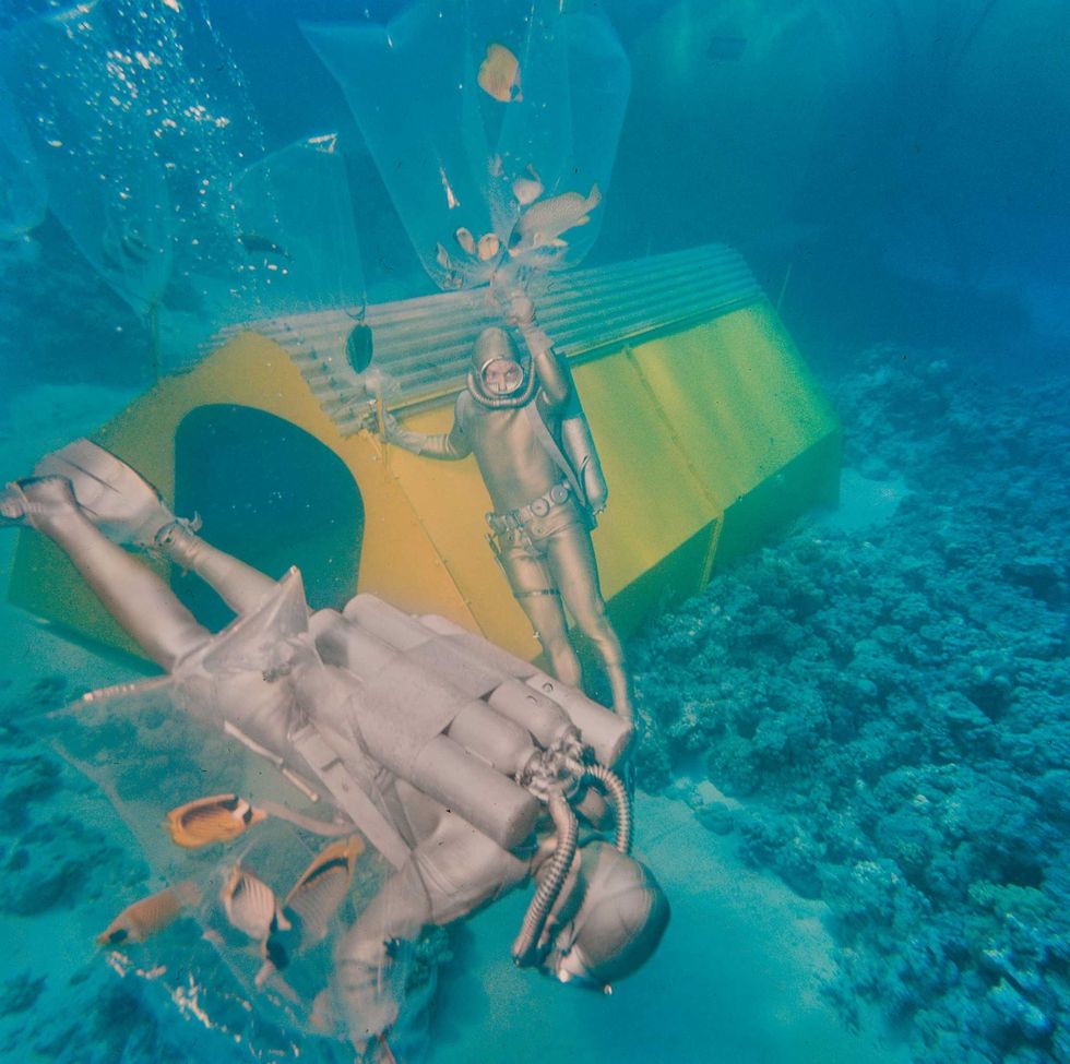 Duikers vangen vissen in de buurt van een van de habitats van Cousteaus experimentele onderwaterdorp waarin vijf duikers een maand lang op diepte verbleven