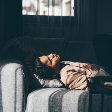 depressed young woman lying on sofa at home