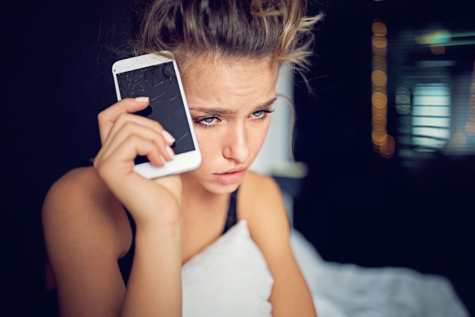 depressed young woman with broken smartphone