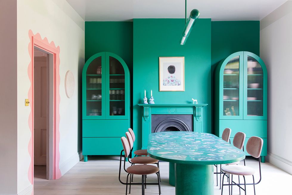 comedor con pared y muebles verde chillón y marco de la puerta en rosa en design house en londres del estudio 2lg