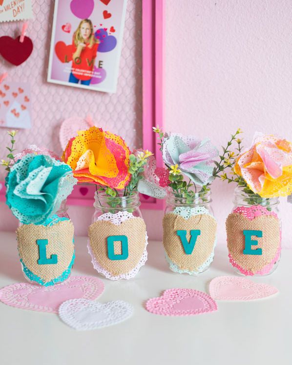 four mason jars with letters on the front spelling out love, filled with flowers made out of doilies