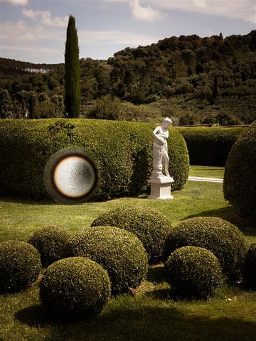 a decorative garden featuring a statue and neatly trimmed hedges