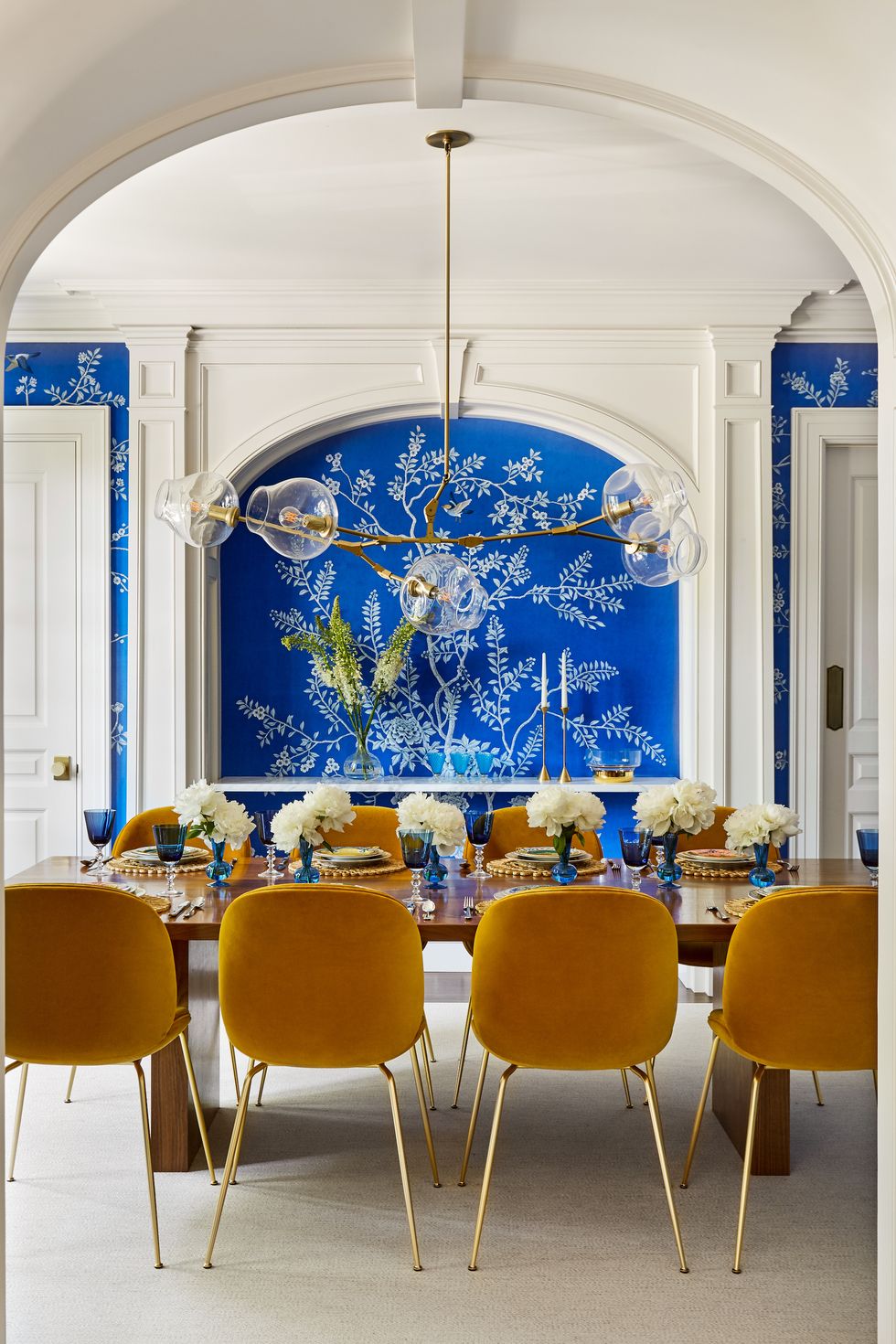 blue wallpaper in a dining room with yellow chairs