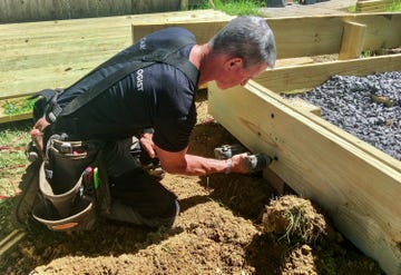 man drilling into wood to build deck