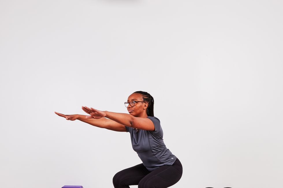 monique lebrun performing a squat as part of the desk exercise series