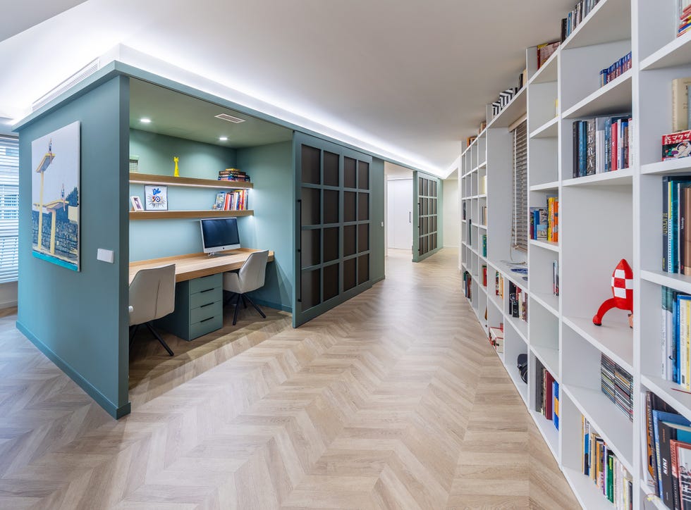 pasillo con módulo verde que integra un despacho con puertas correderas y librería blanca en la pared derecha