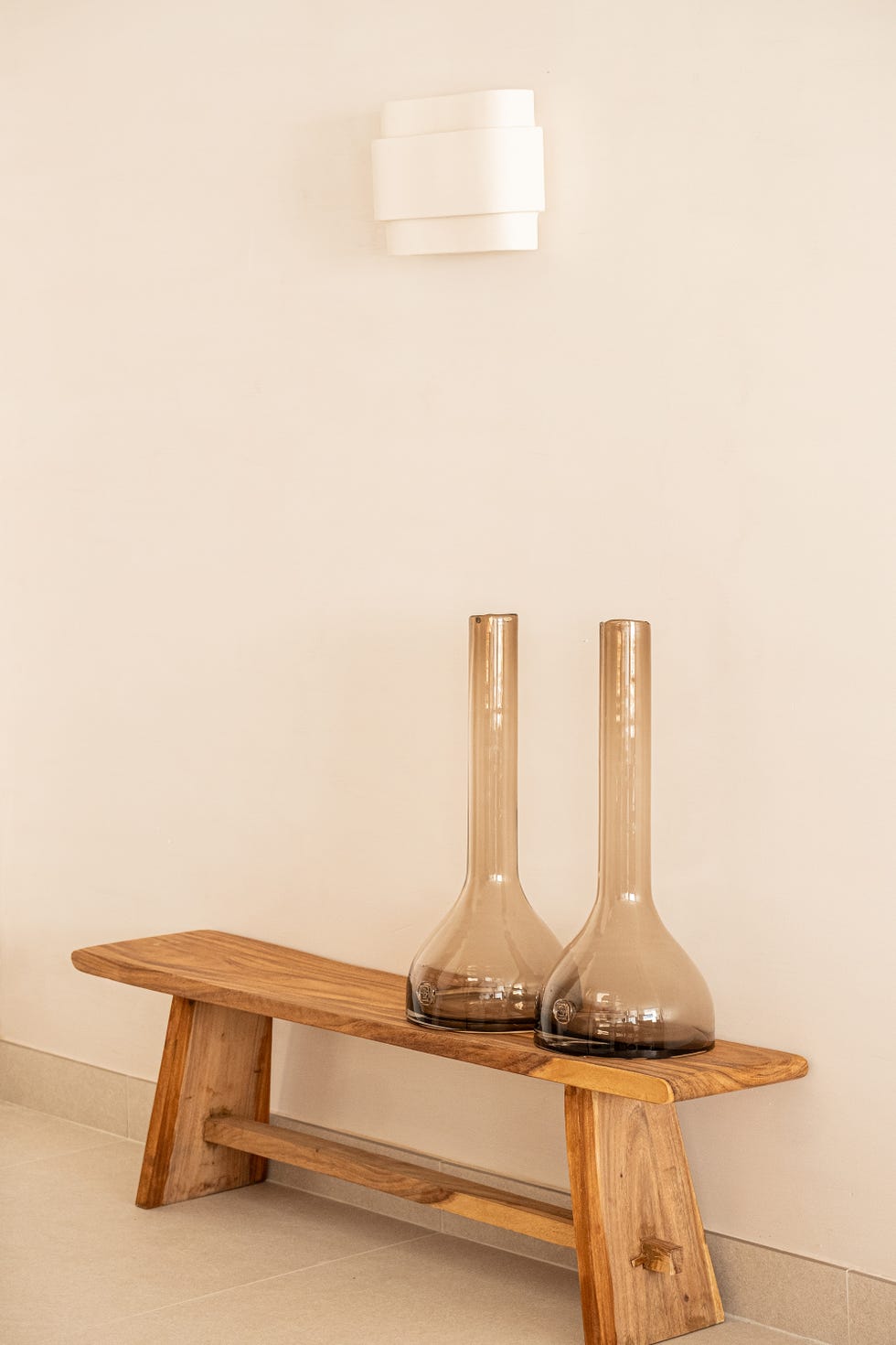 banco de madera con jarrones de vidrio y aplique de pared