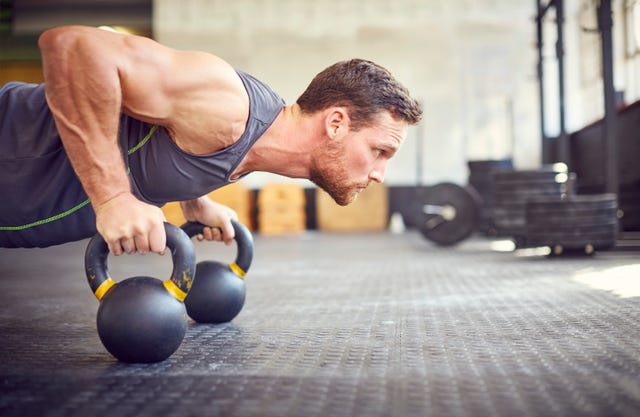Determined athlete doing push-ups on kettlebells in gym