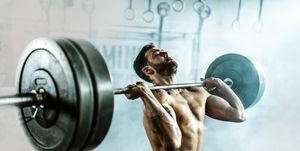 determined athletic man lifting heavy barbell in a gym