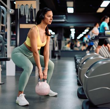 determined athletic woman performing kettlebell squats in the gym